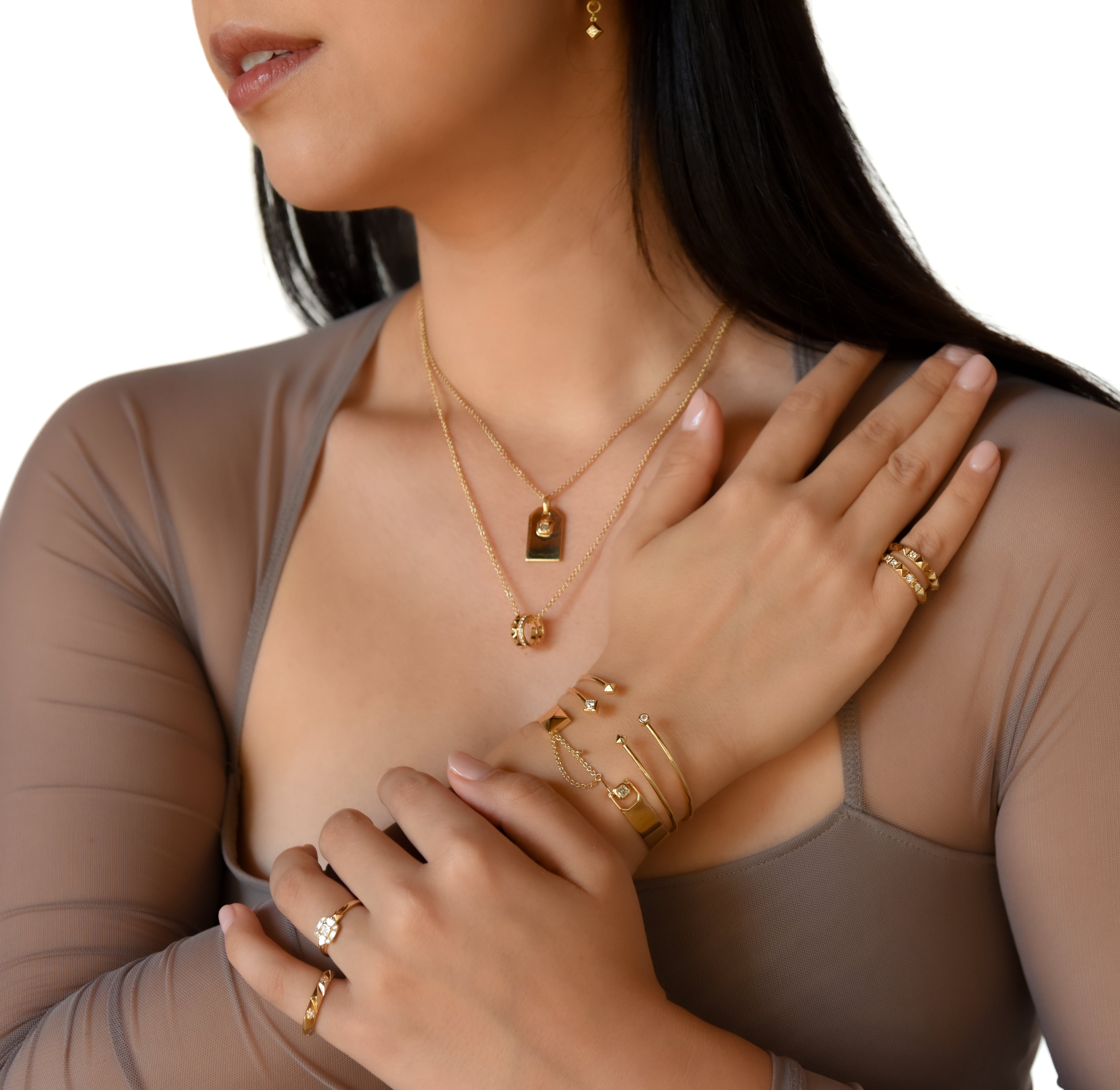 Female model wearing earth origin, ascent, summit and peak earrings, rings, bracelets, and necklaces set in modern electrum.  Ekati Natural diamonds.