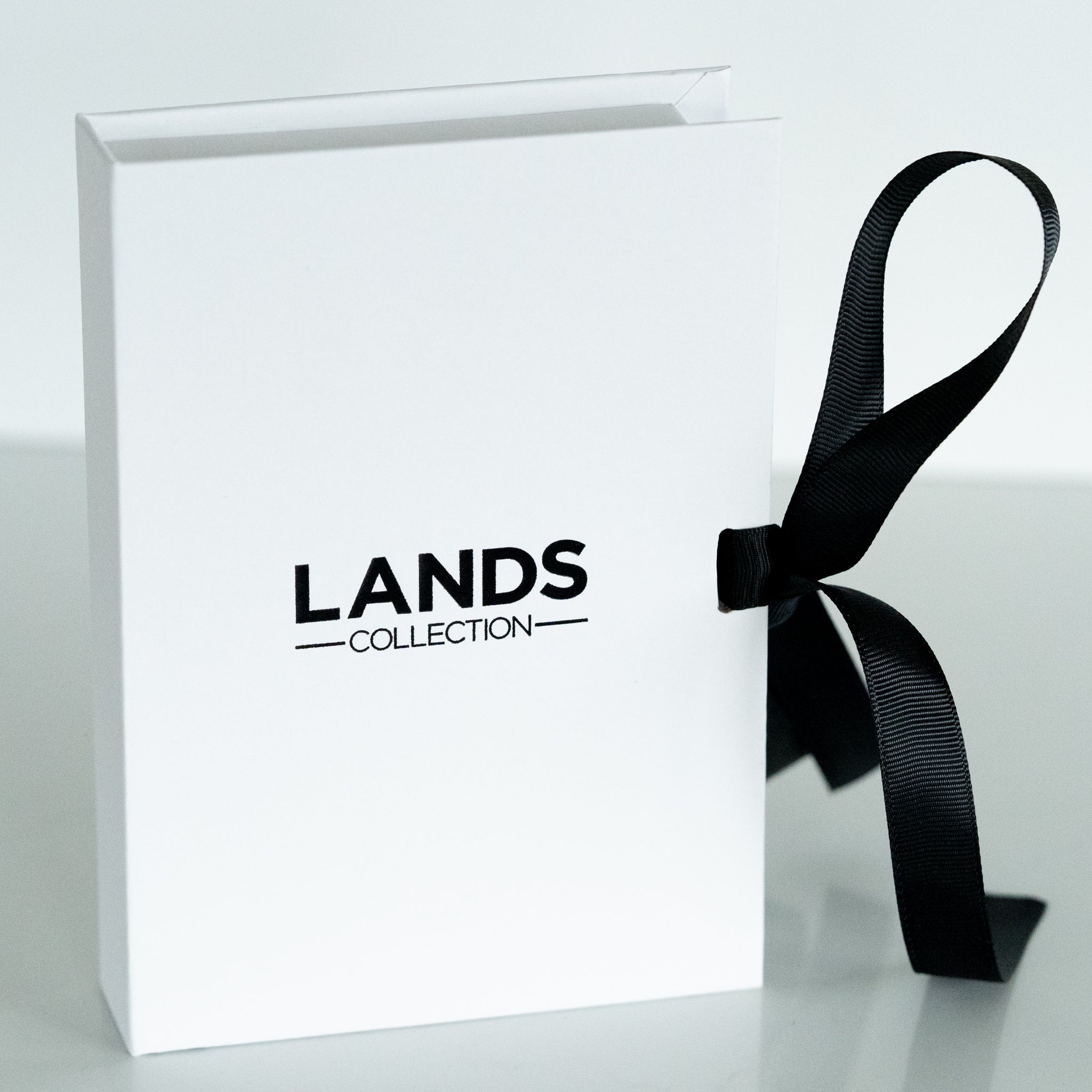 White 7 x 5 x 1 inch branded gift box with white silk ribbon on white background