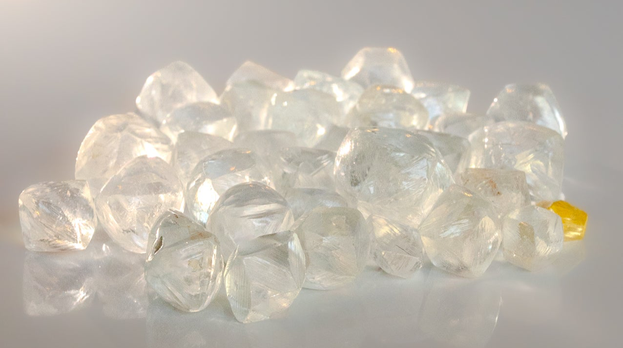 Loose rough natural Canadian diamonds of varying clarity and color on a white background fancy yellow